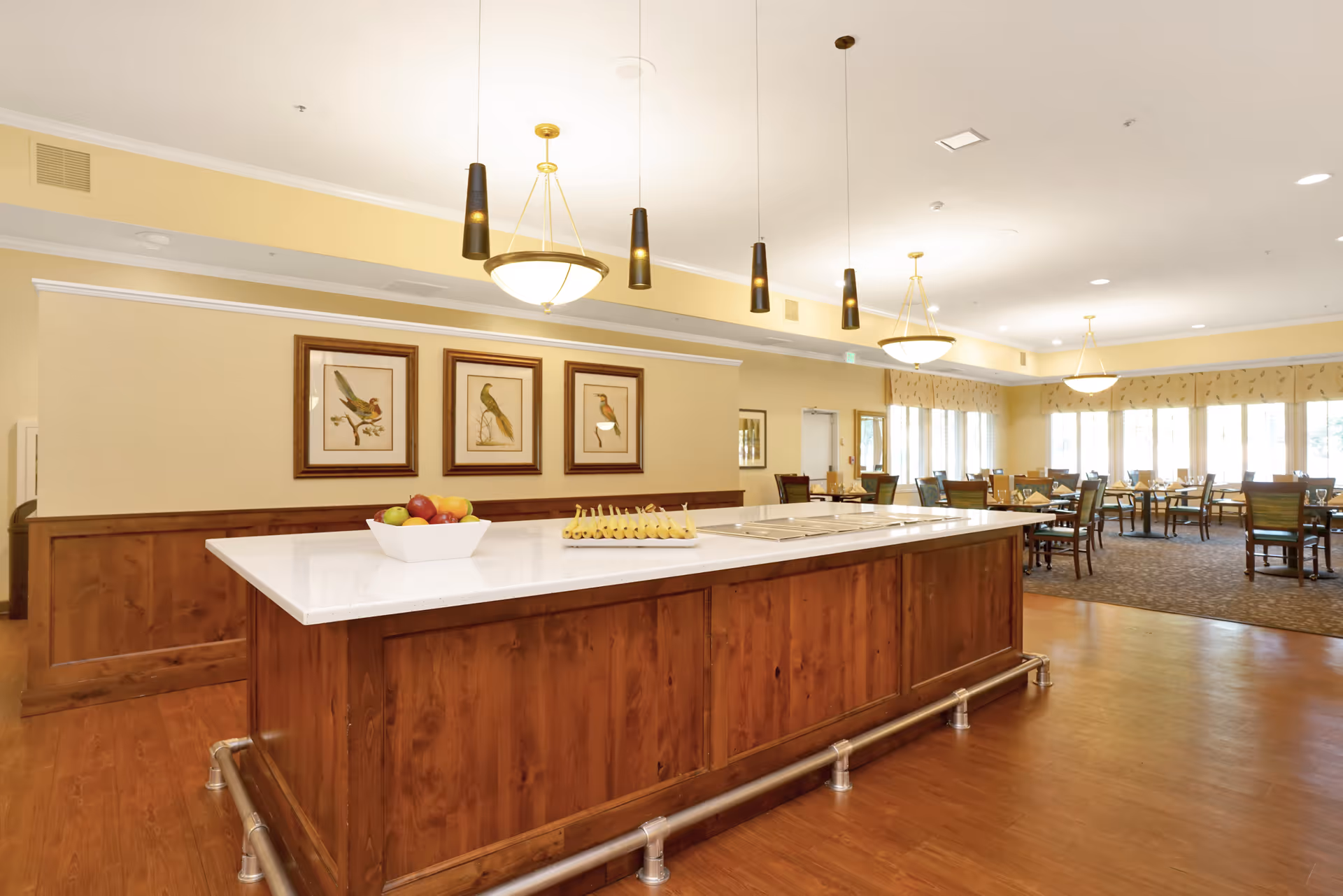 Spacious dining room with a central wooden island topped with a white countertop, pendant lights, and multiple dining tables and chairs.