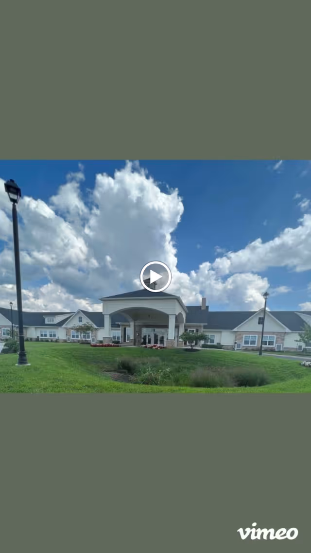 Front exterior view of Silverado Frederick Memory Care Community building with a covered entrance, green lawn, and a partly cloudy blue sky.
