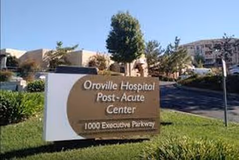 Outdoor sign for Oroville Hospital Post-Acute Center with surrounding greenery.