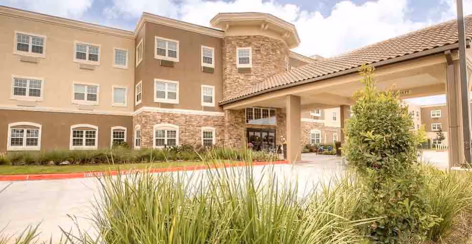 Exterior view of Laurel Glen at Sugar Land, tan-brick senior living building with entrance.