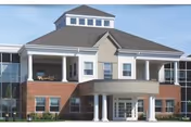 Front exterior view of a two-story building with a combination of brick and light-colored siding, featuring a covered entrance supported by white columns and a small tower-like structure on the roof.