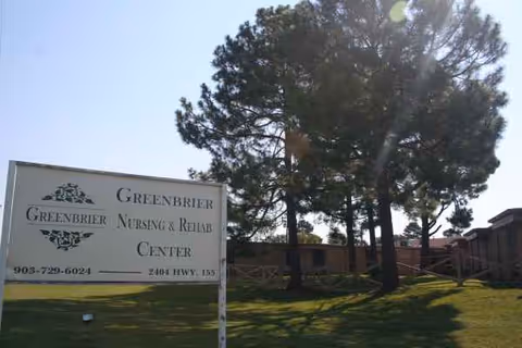 Front view of Greenbrier Nursing and Rehab Center sign beside trees.