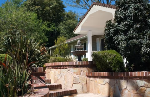 Front exterior of Lafayette Residential Care with stone wall, steps, and a fountain.