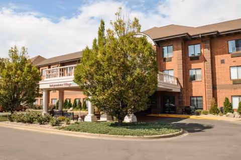 Exterior view of Independence Village of Peoria with a brick building and trees.
