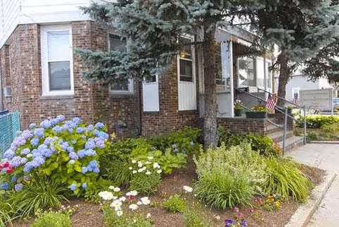 Front exterior of Eastgate Nursing & Rehabilitation Center with brick facade, entrance, and colorful landscaping.