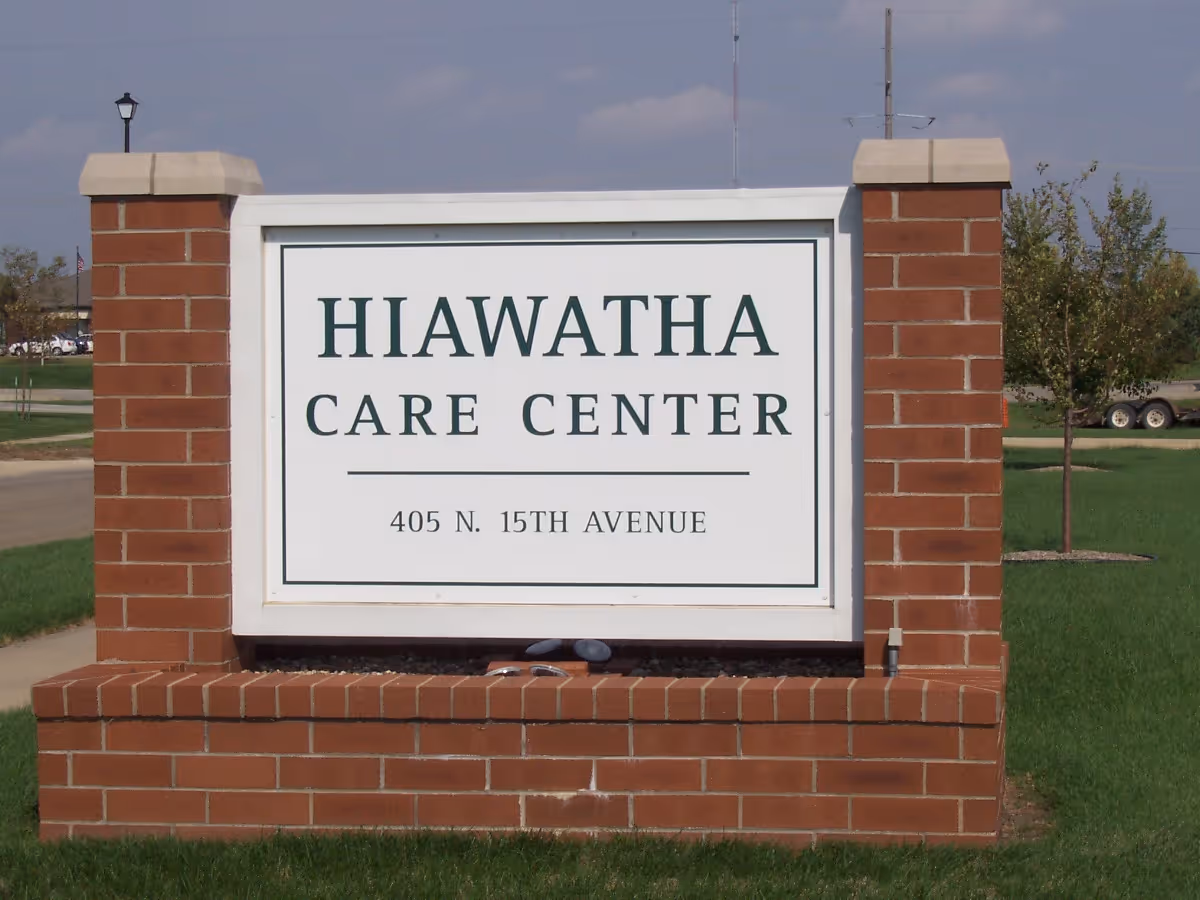 A brick monument sign on a lawn reading Hiawatha Care Center, 405 N. 15th Avenue.