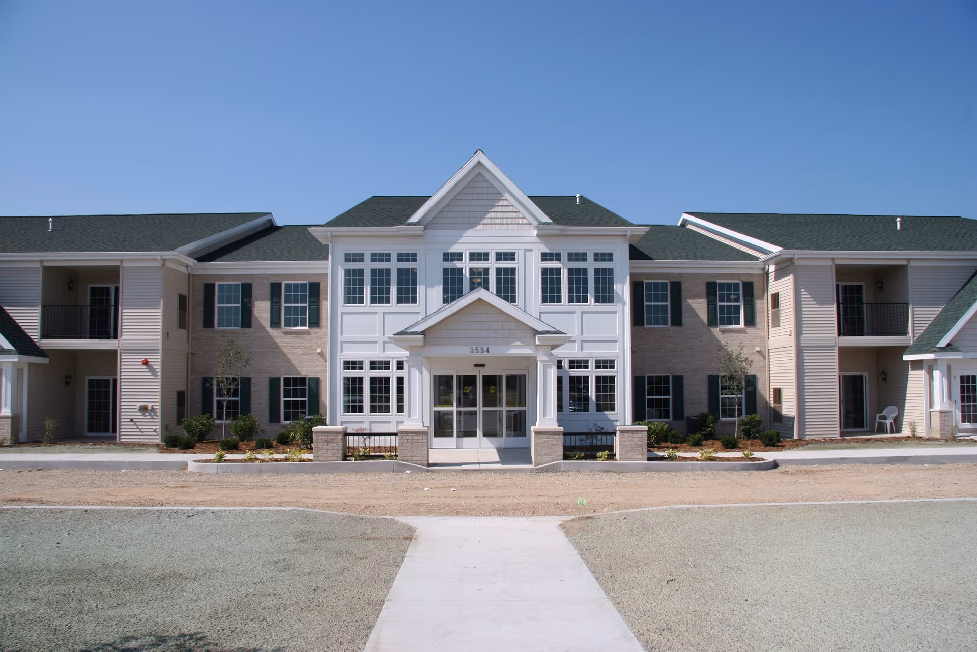 Front exterior of a two-story senior living building with a central entryway and symmetrical windows.