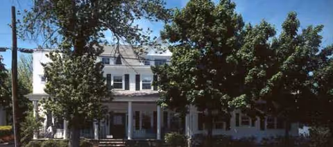 Thomas Upham House Rehabilitation & Skilled Nursing Center exterior, white building with columns and surrounding trees.