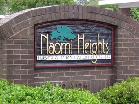 A brick arch sign reads Naomi Heights Nursing & Rehabilitation Center, LLC, with greenery nearby.