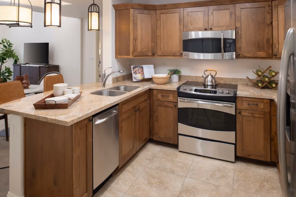 Modern kitchen with wooden cabinets, stainless steel appliances, granite countertops, and an island sink with seating.