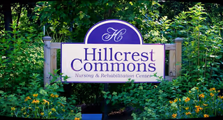 Hillcrest Commons Nursing sign surrounded by greenery outdoors.