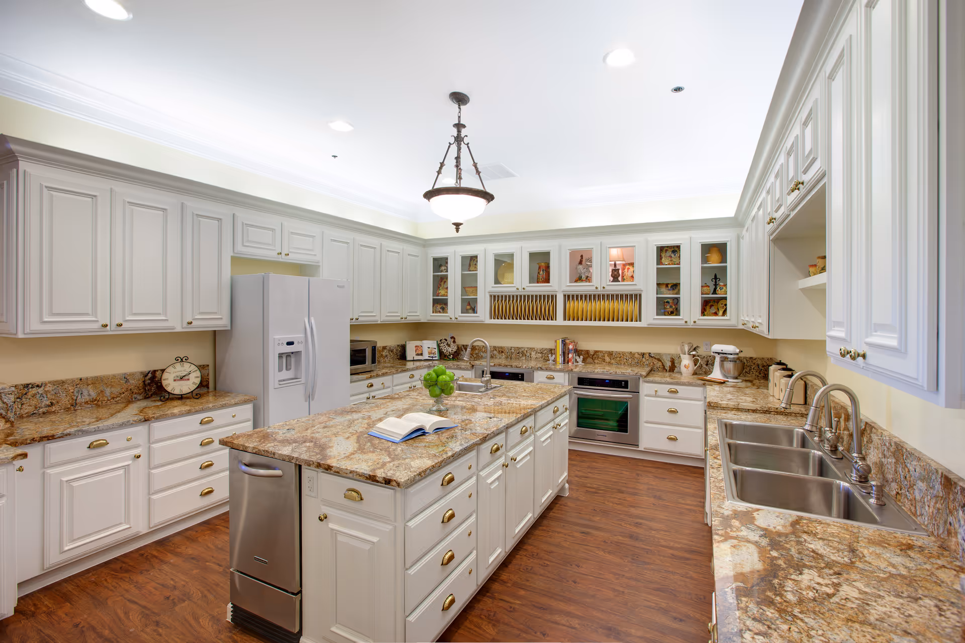 Bright, spacious kitchen with white cabinets, granite countertops, and a central island.