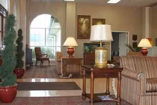 Hotel-style senior living lobby with seating groups, lamps, and artwork.