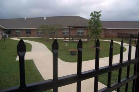 Front exterior of Willow Ridge Nursing & Rehab, brick building with curved walkway and black fence.
