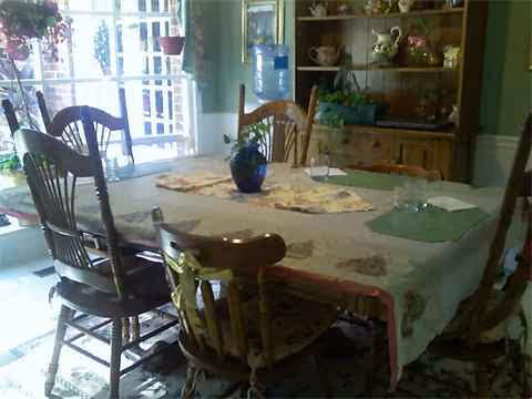 The Willows dining room features a table with chairs, a china cabinet, and sunlit glass doors.