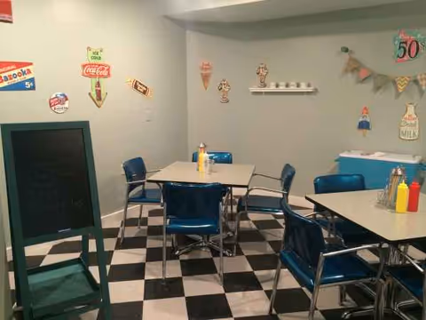 Blue retro dining area with checkered floor, tables, and chairs in a senior living facility.