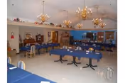 Bright dining room with long blue tablecloths, chairs, and chandeliers in a senior living facility.