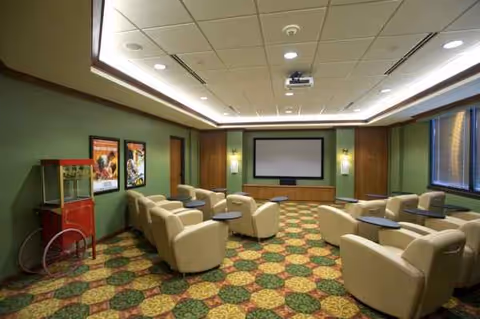 Interior lounge at Morningside Ministries at the Meadows with cream chairs and a projector screen.