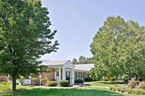 Single-story Milford Center exterior with manicured lawn, trees, and a covered entrance.