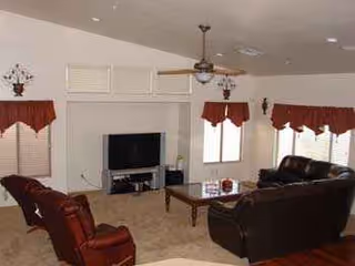 Spacious living room in a senior facility with leather couches and a central coffee table.