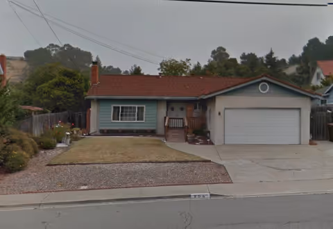 Single-story house with a two-car garage, small front porch, and lawn facing a residential street.