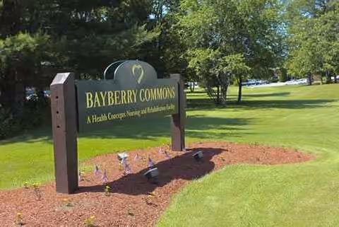 Bayberry Commons sign on manicured lawn with trees and mulch