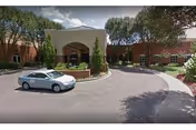 Front exterior of a senior living building with circular driveway and parked car.