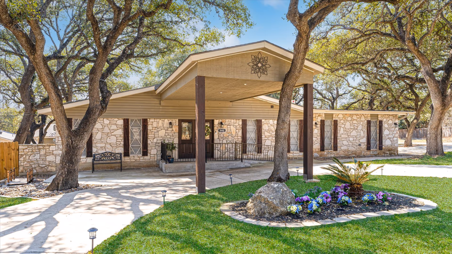 Stone exterior of a senior living facility with a covered entrance and landscaping.