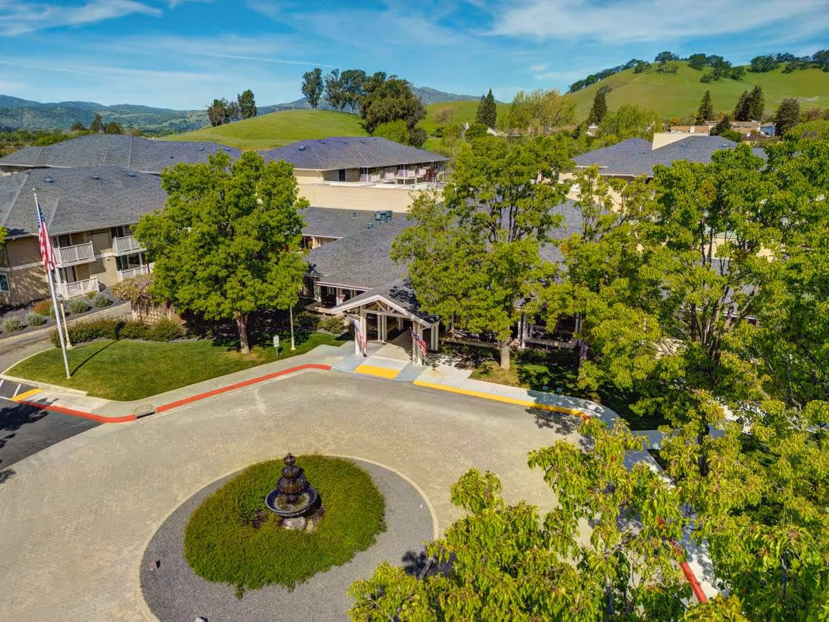 Aerial view of The Village at Rancho Solano entrance featuring a circular driveway, fountain, and surrounding greenery.