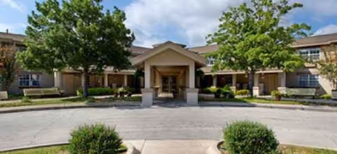 Front view of Brayden Park Assisted Living building with driveway, trees, and entrance walkway.