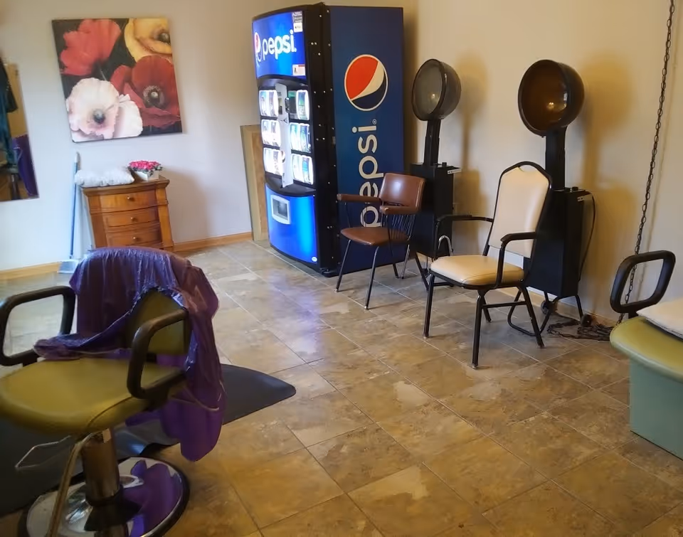 Interior salon area with styling chairs, two hooded hair dryers, and a Pepsi vending machine.