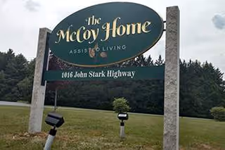 Outdoor sign for The McCoy Home Assisted Living on a grassy lawn.