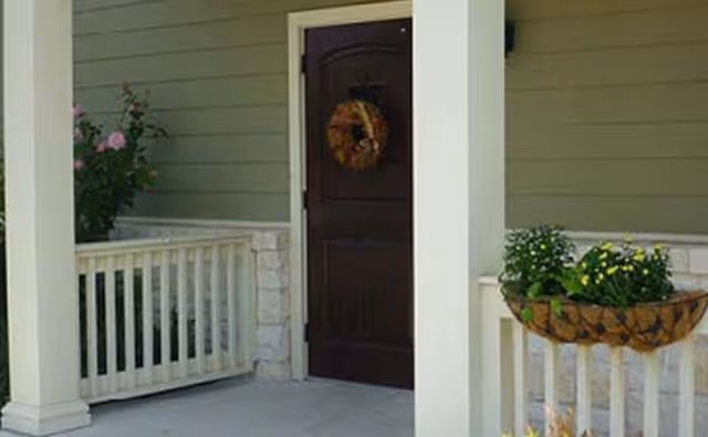 Front porch of Morning Star Memory Care featuring a dark door, wreath, and planters.