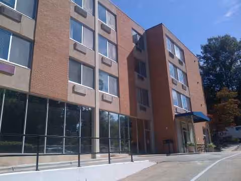 Exterior view of a brick building with large windows and an entrance with a blue awning.