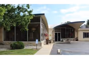 Exterior view of Miller's Merry Manor entrance with curved awning and glass doors.