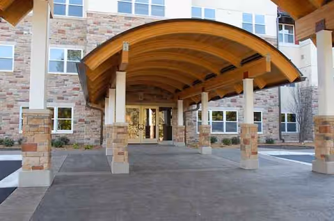 Front entrance of The Glenn Minnetonka with a curved wooden canopy and stone columns.