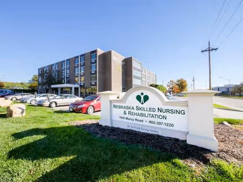 Exterior view of a nursing and rehabilitation facility with a sign and parked cars.
