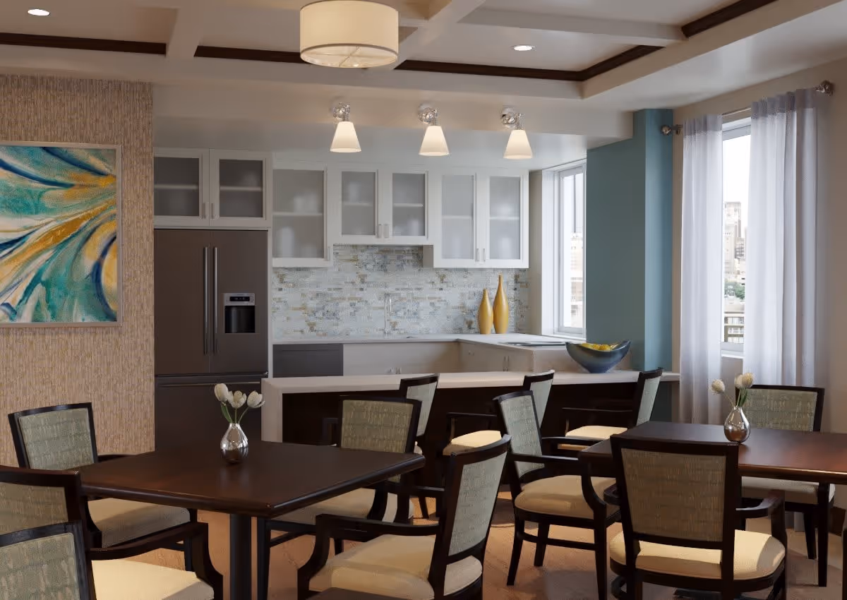 A modern dining area with several dark wood tables and cushioned chairs. In the background, there is a kitchen with white cabinets, a stainless steel refrigerator, and a tiled backsplash. The room is decorated with a colorful abstract painting on the left wall, two yellow vases on the kitchen counter, and small flower vases on the tables. Large windows with sheer white curtains allow natural light to fill the space.