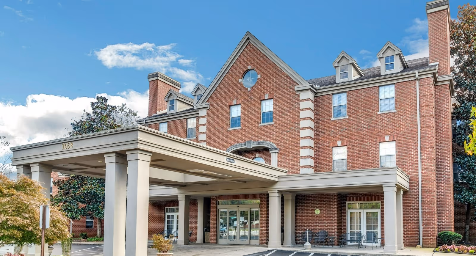 Brick assisted living building with a covered entrance and parking area.