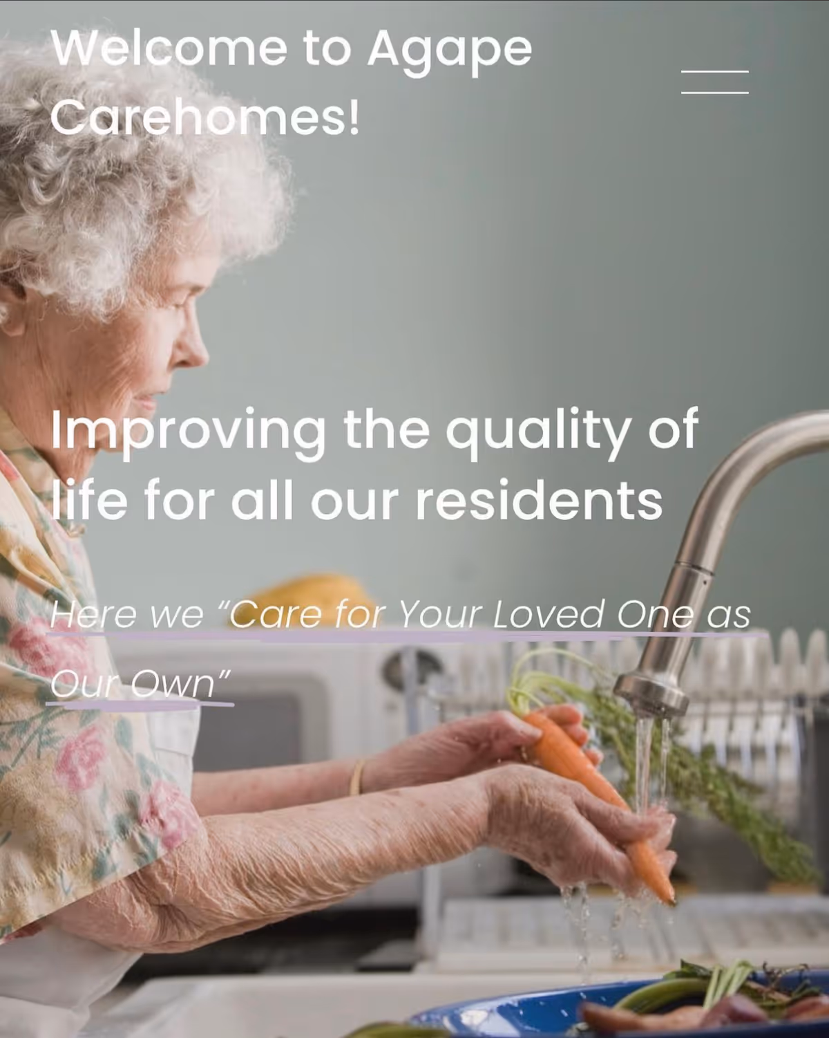 An elderly woman washing fresh carrots under a kitchen faucet in a care home kitchen setting.