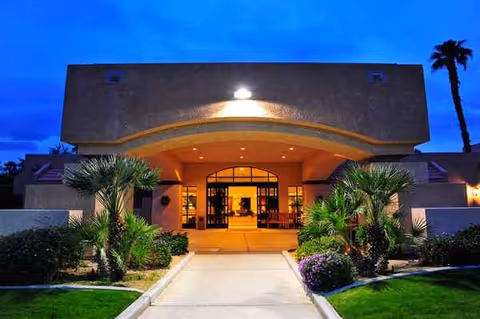 Exterior view of The Carlotta entrance with arches, plants, and walkway.