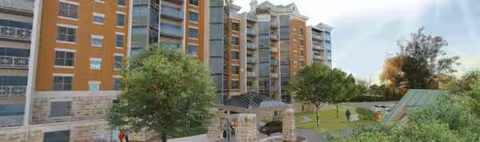 Outdoor courtyard of a multi-story senior living building with trees and people walking.