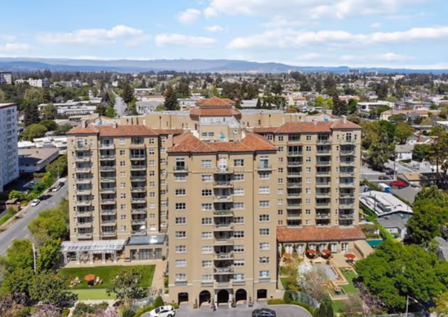 Aerial view of The Peninsula Regent, showcasing its beige facade, red-tiled roof, and surrounding greenery.
