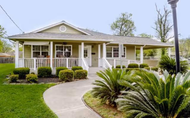 Single-story assisted living home with a front porch, white railings, and landscaped entrance.