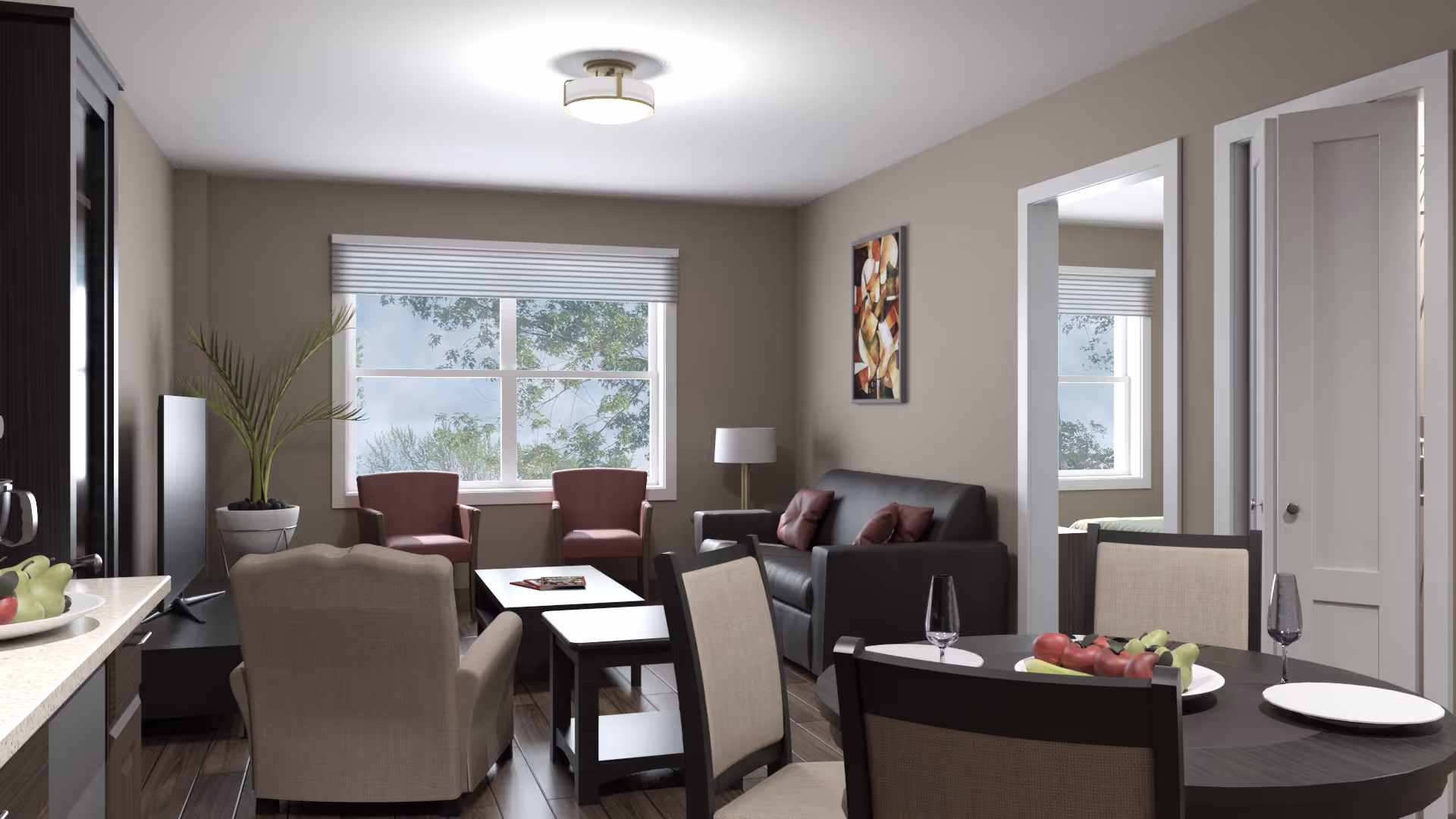 A cozy living room and dining area with a large window showing trees outside. The room features a gray sofa with red cushions, two red armchairs, a beige armchair, a black TV stand with a flat-screen TV, a round dining table with four chairs, and a bowl of fruit on the table. There is a floor lamp next to the sofa, a potted plant near the window, and a colorful abstract painting on the wall. A doorway leads to another room with a bed visible.