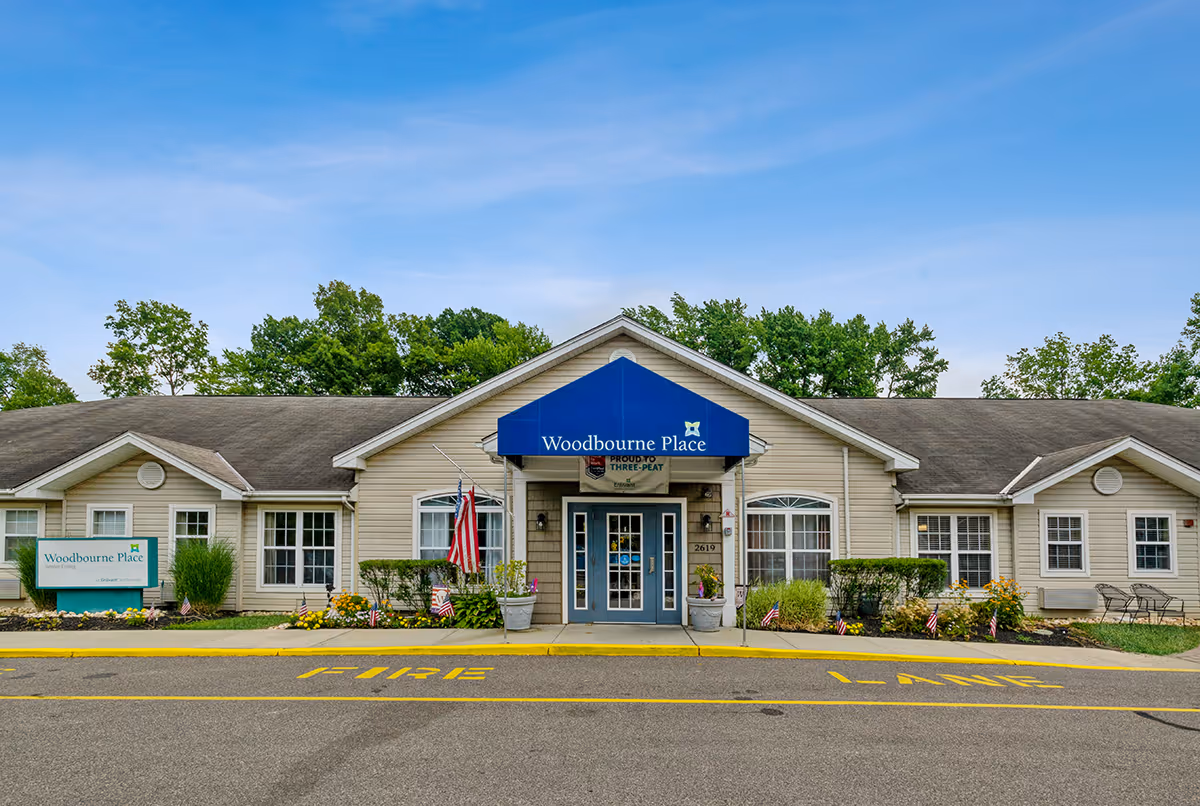 Front view of a single-story senior living facility with blue Woodbourne Place awning and entrance.