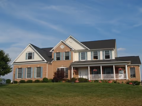 Two-story brick and siding senior living facility with a covered front porch and well-kept lawn.