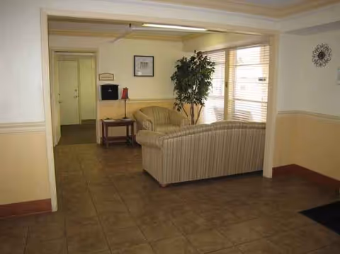 Lobby seating area with striped sofas, a plant, and large windows.