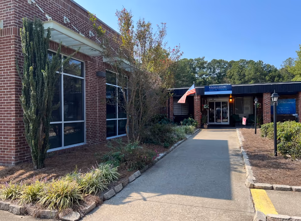 Brick-front entrance of Edgecombe Health Center with a walkway, landscaping, and an American flag.