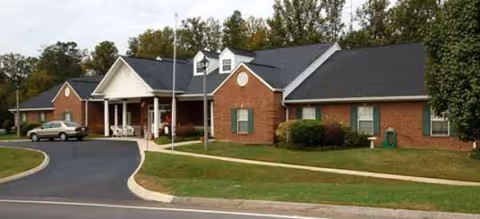 Brick senior living facility with front entrance, circular driveway, and manicured lawn.